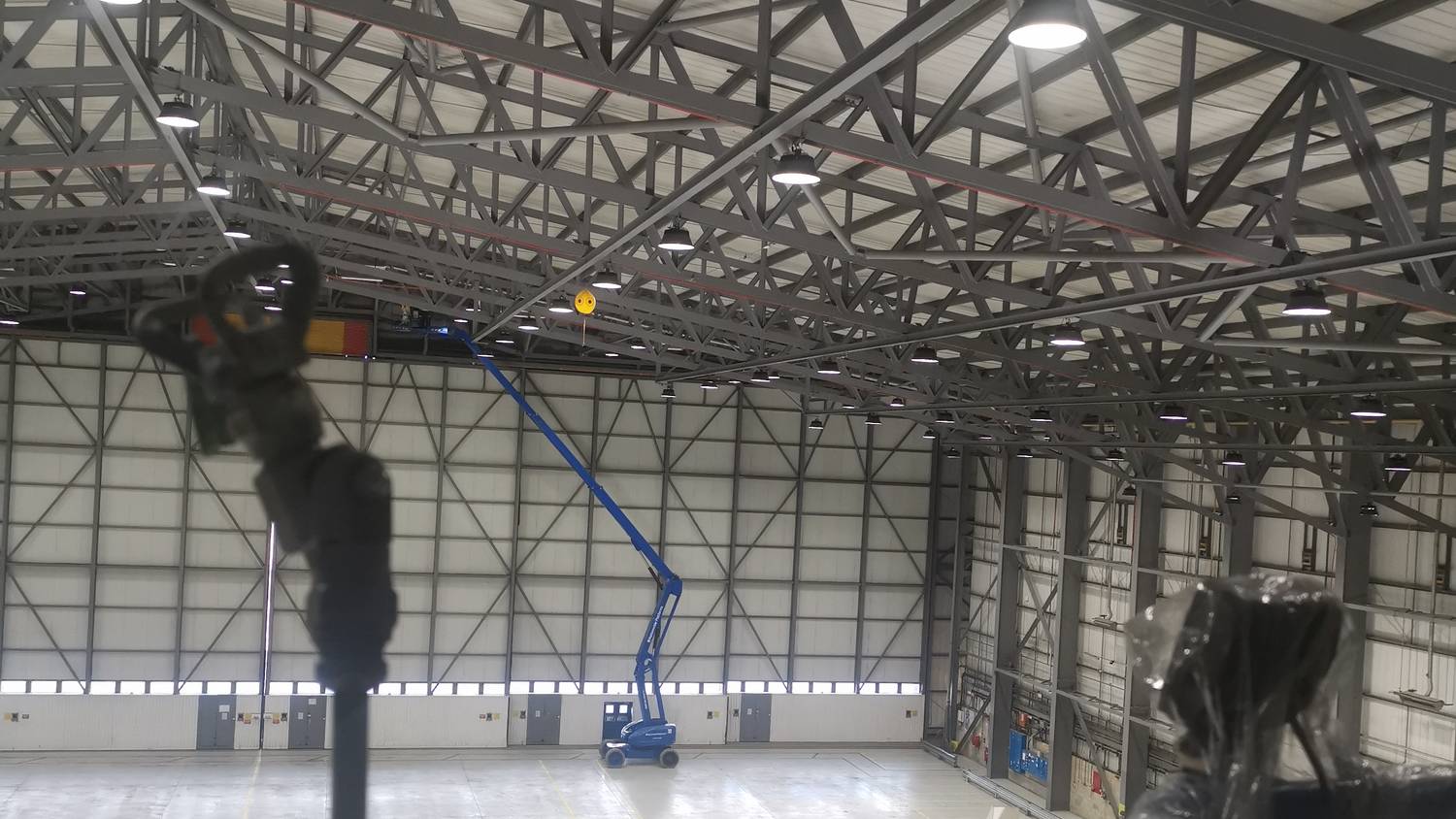 Hangar roof trusses being airless sprayed with a MEWP on the hangar floor – Fixidea Coatings Ltd